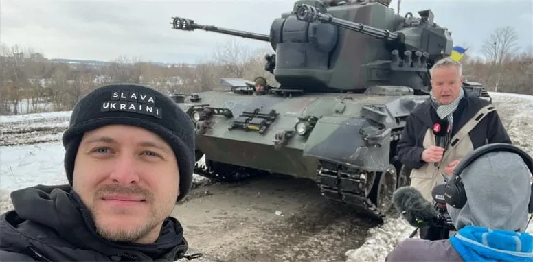 Reporting next to military equipment